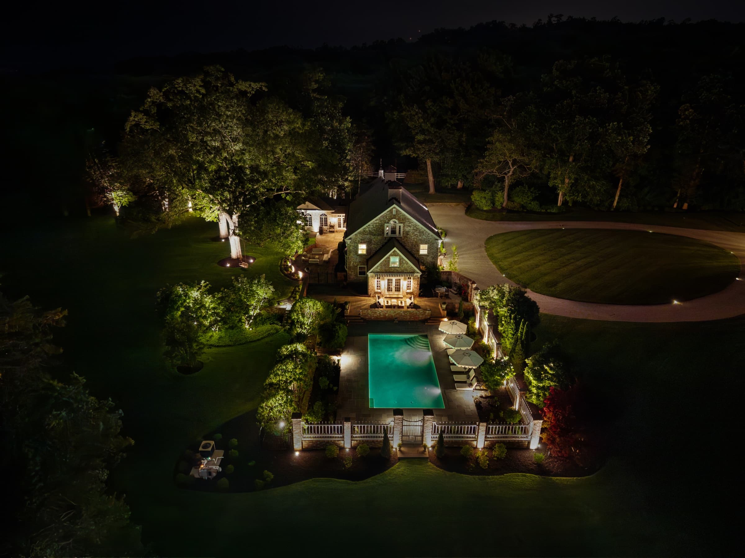 The property from above, garage bays and drive picked out in warm light