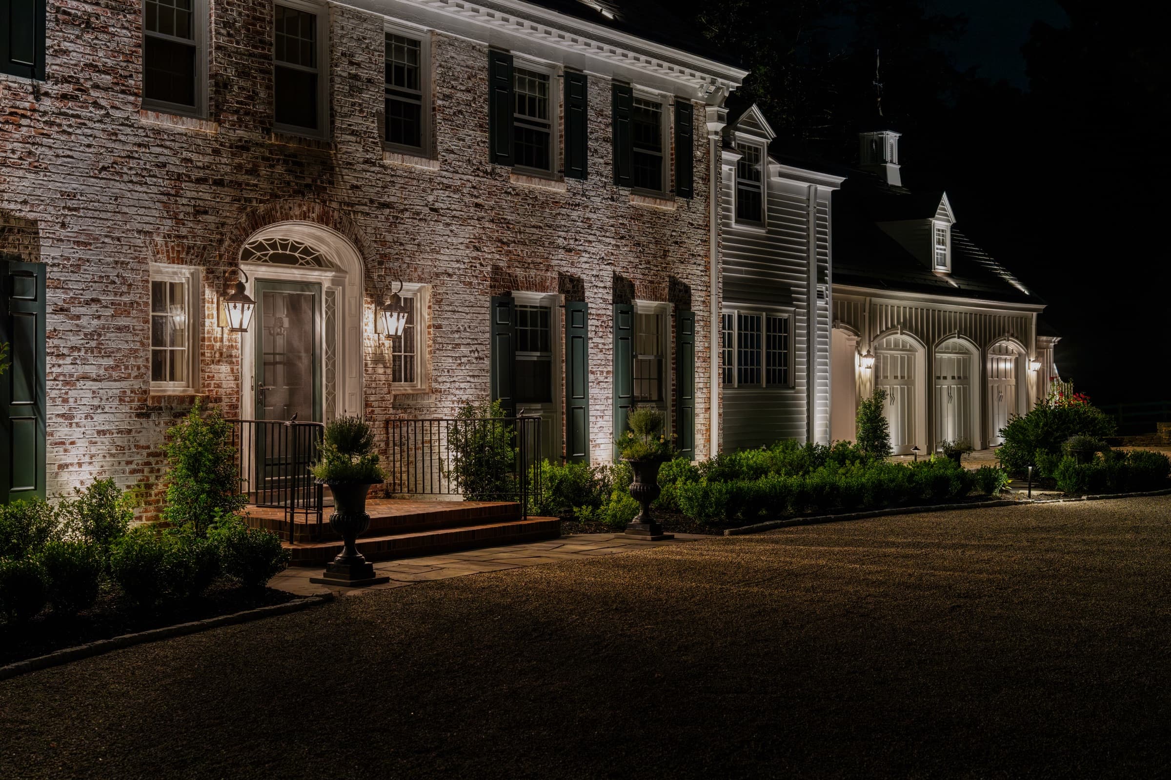 Front entrance in close view: grazed brickwork, urns and lit steps